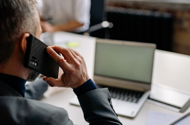 assistenza - persona al cellulare davanti al pc